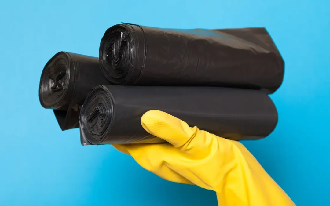 Picture of hand in a yellow glove holding biodegradable garbage bags.