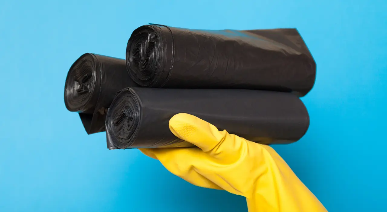 biodegradable-garbage-bags-trash-services-north-carolina Picture of hand in a yellow glove holding biodegradable garbage bags.